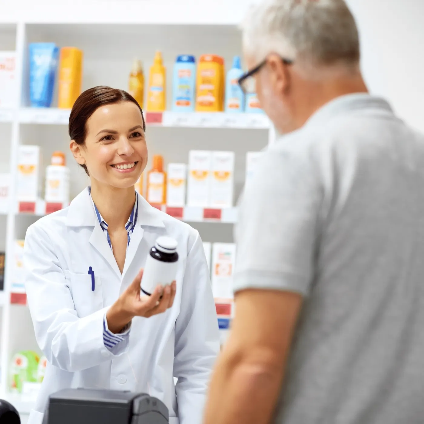 A pharmacist explains a medication to an older patient at the pharmacy counter