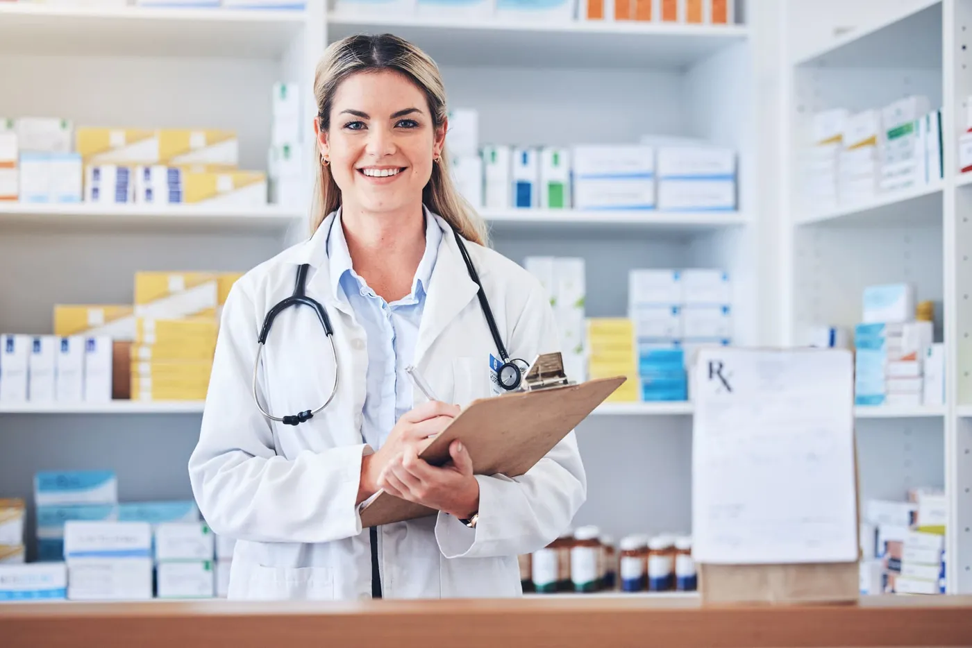 A pharmacist holding a clipboard in a pharmacy aisle